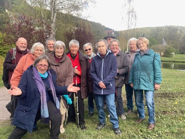 Eine Gruppe älterer Wanderer steht auf einer Wiese. Sie lachen fröhlich in die Kamera. 
